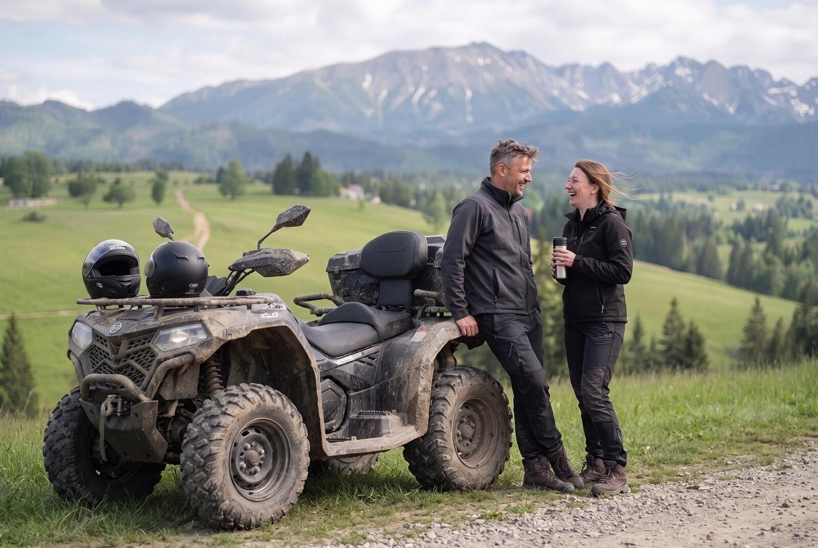 Para rozmawia oparta o zabłoconego quada na postoju przy szutrowej drodze, kaski na kierownicy, w tle Tatry