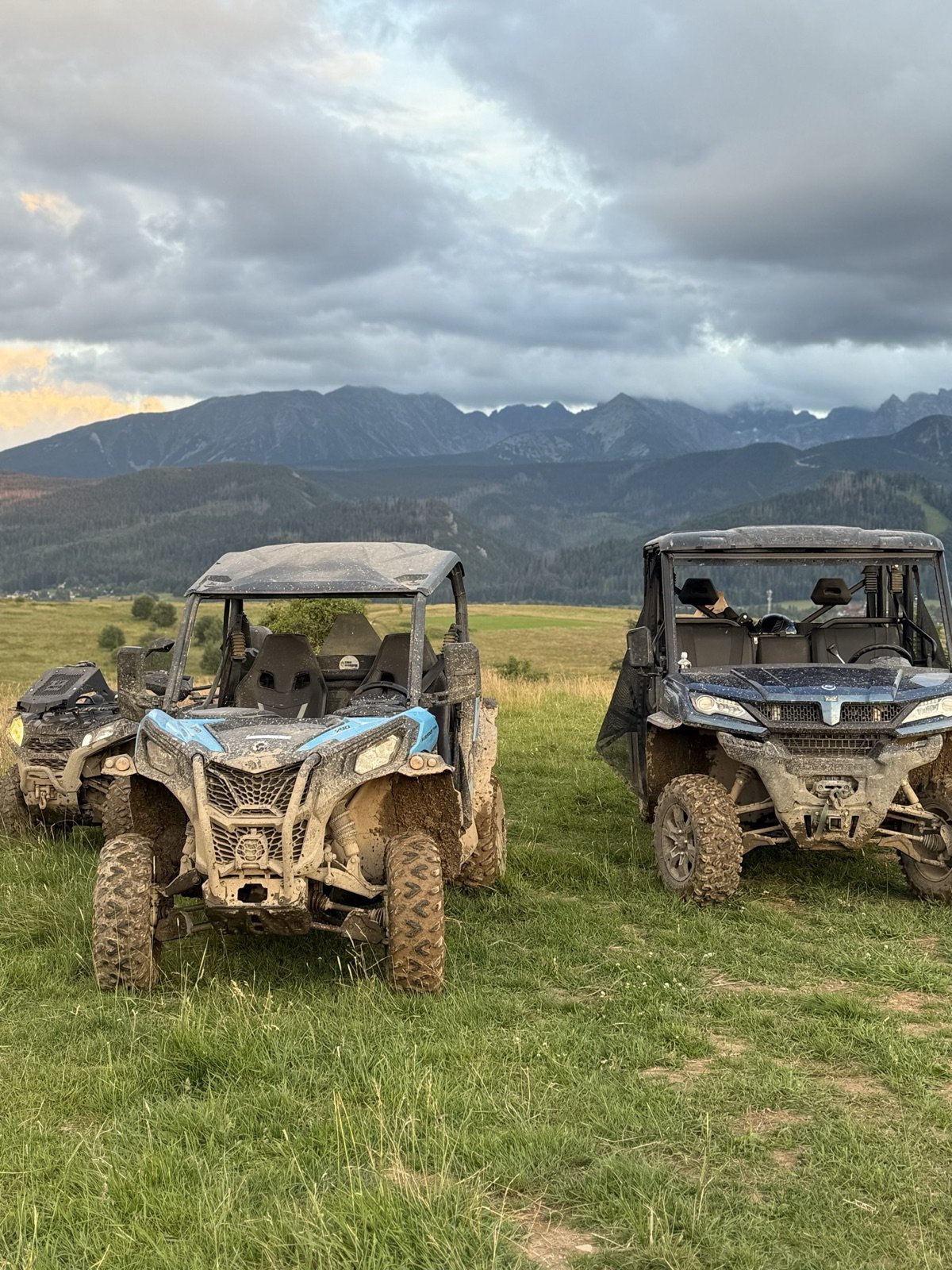 Dwa zabłocone buggy na łące o zmierzchu, na horyzoncie Tatry